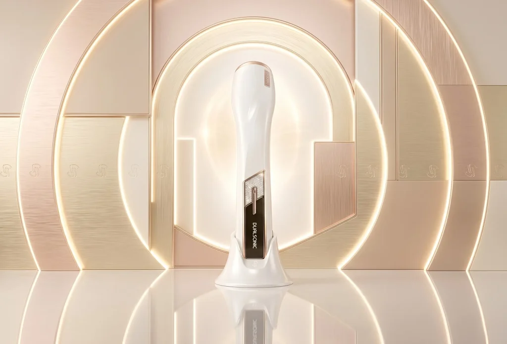Dualsonic Maximum Alpha at-home skincare device and stand, presented in a glowing geometric gold and champagne luxury display, suitable for a product FAQ header.